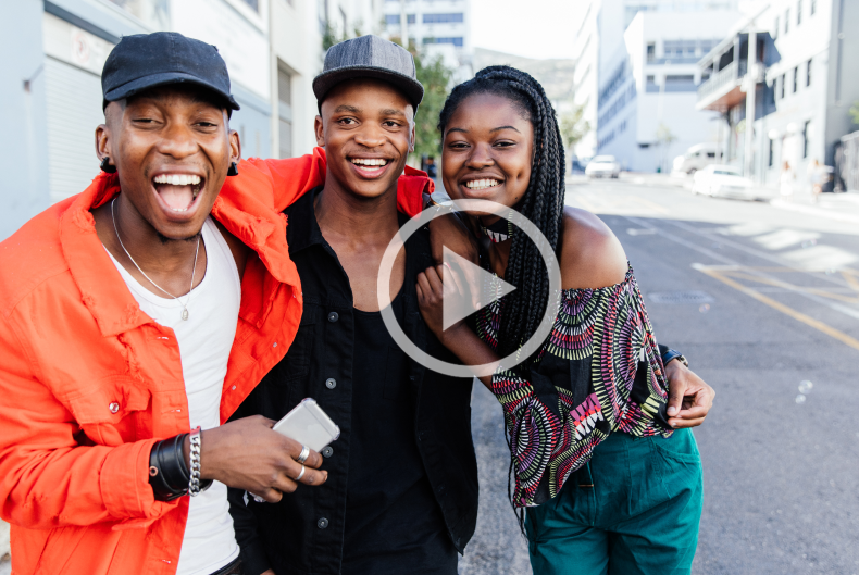 Three friends in street with arms around each other